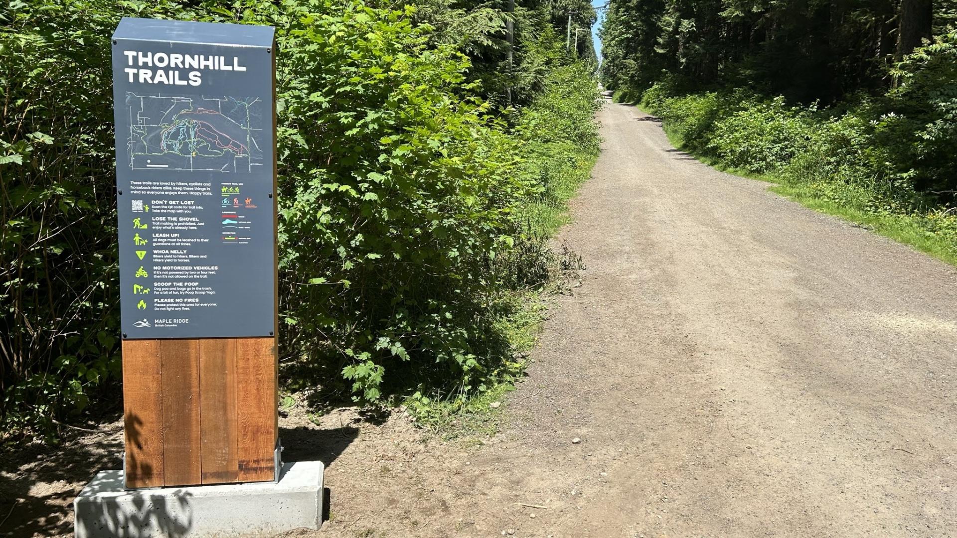 Thornhill trails sign to the left of a wide gravel trail through the forest